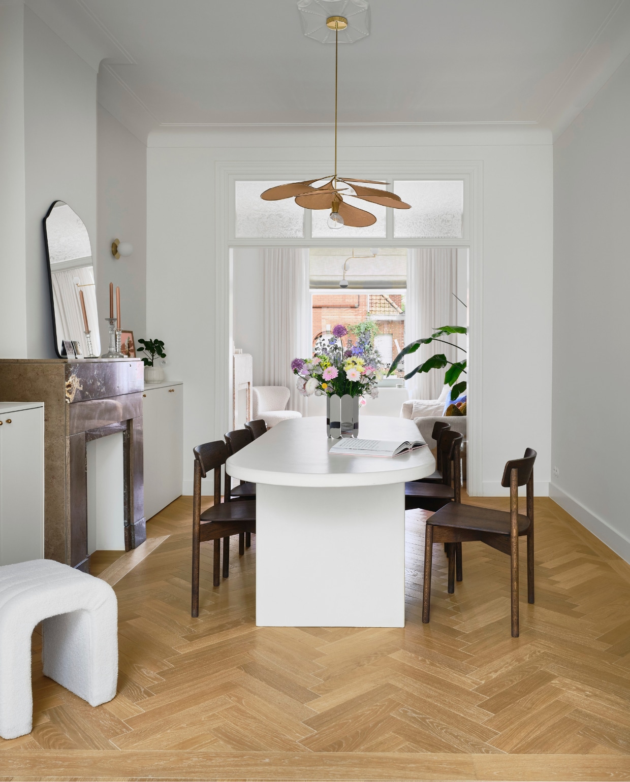 Wandkasten maatwerk naar eigen ontwerp. Messing kastgreepjes en deurklinken Dauby. Poef Kwantum. Tafel maatwerk, afgewerkt met microtopping van B.a.i.t. Stoelen Takt. Hanglamp Georges. Wandlampen H&m Home. Vaas spiegelglas Muller Van Severen voor Hay. Spiegel Zara Home. Vintage kandelaars. Waterfles Paveau. Eiken visgraat parket Avance in Valetta via Hout Luyten.