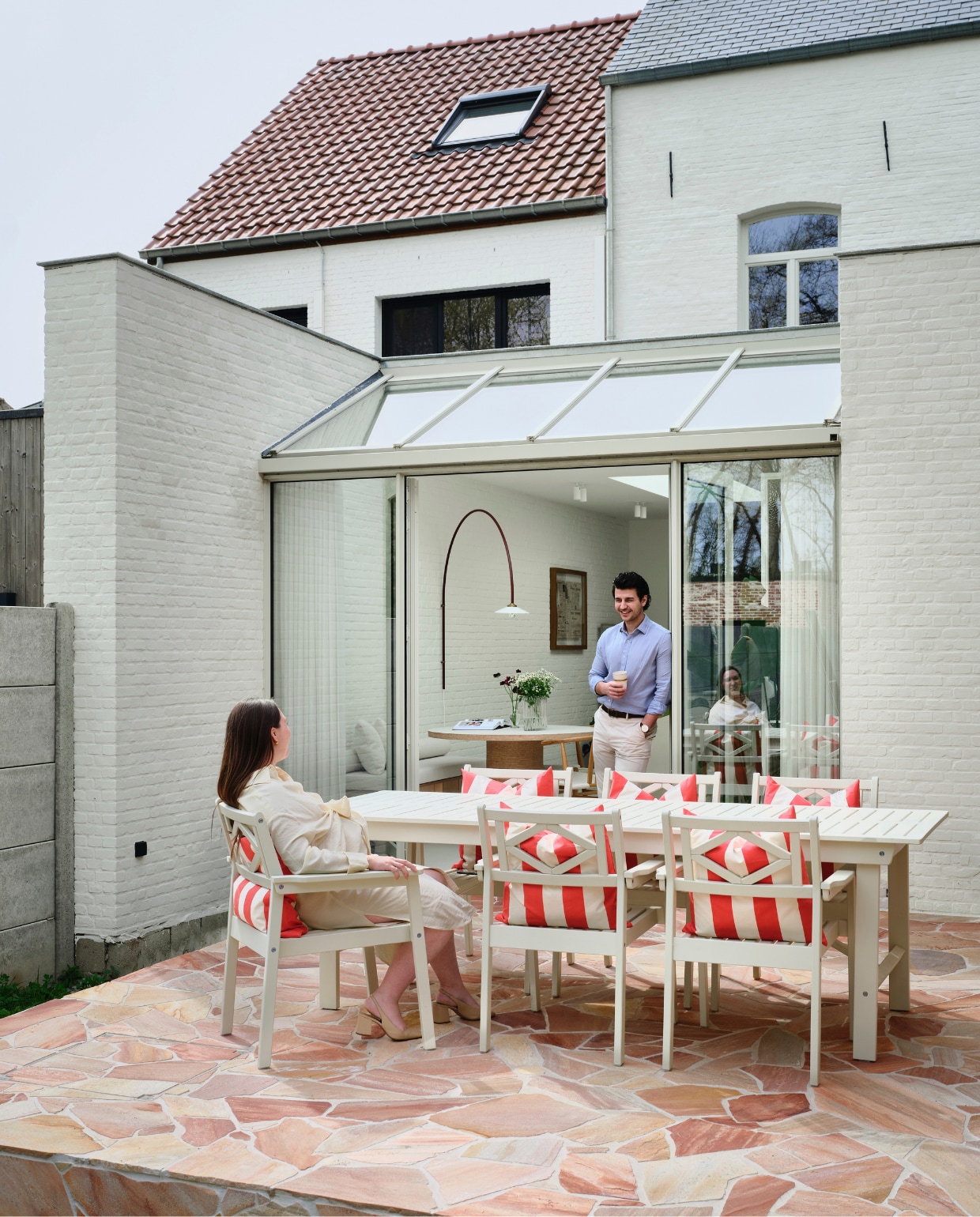 Vloer Flagstone Romano Rosé van Hb-classics. Tafel en stoelen Ikea. Kussens H&m Home. Lamp Muller Van Severen. Afwerking gevel Kalei in Ivory van Stoopen & Meeus, met extra witpigment. Kleur serre Ral 7032. vtwonen 07-2026 | fotografie Mr. Frank