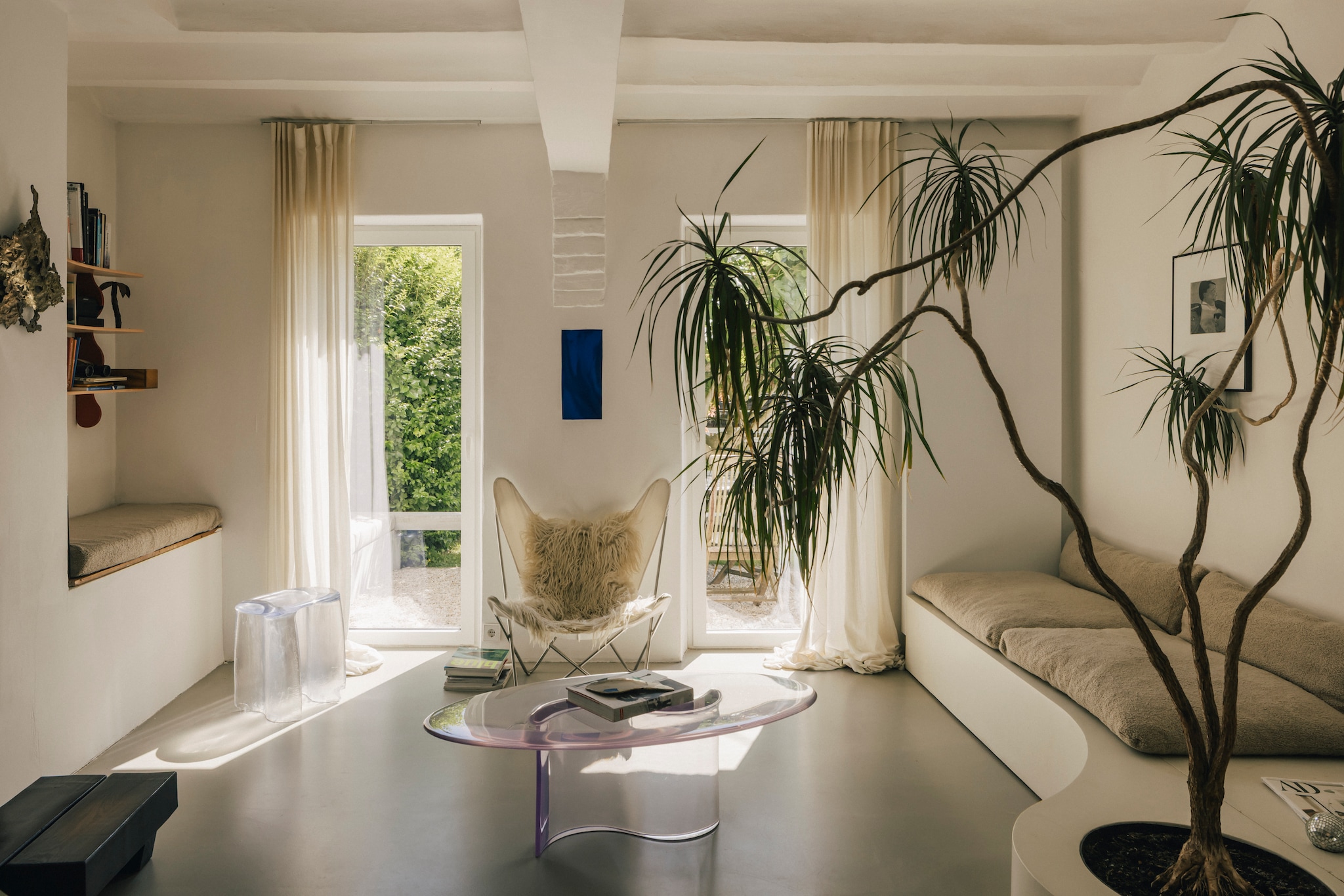 Stoel Butterfly van Jorge Ferrari Hardoy voor Knoll. Salontafel en kruk Liquid van Lukas Cober. Gordijnen kaasdoek gekleurd met kurkuma van Lukas Cober. LP Yin Yin. Plant Drakenbloedboom. vtwonen design 8-2026 | Fotografie Katoo Peeters