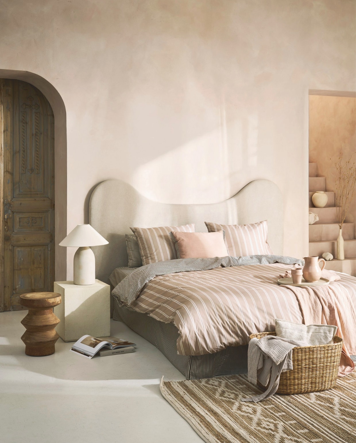 vtwonen dekbedovertrek Fun Stripe, katoen, naturel, vanaf € 59,95, vtwonen sierkussen Cozy Slub, katoen en polyester(vulling), 60x40 cm (lxb) € 44,95, vtwonen bedsprei Gentle Embrace, katoen mousseline, soft pink, vanaf € 59,95.M.m.v. stoffeershop.nl (op maat gemaakt headboard), romo.com (stof Linara, gebruikt voor headboard), deens.nl (vloerkleed), nordal.eu (mand), versmissen.nl (houten bijzettafel), zarahome.com (tafellamp, cementen bijzettafel), burbriantiek.com (oude deuren), shop.vtwonen.nl (badjas Gentle Embrace van vtwonen). Overig privébezit.