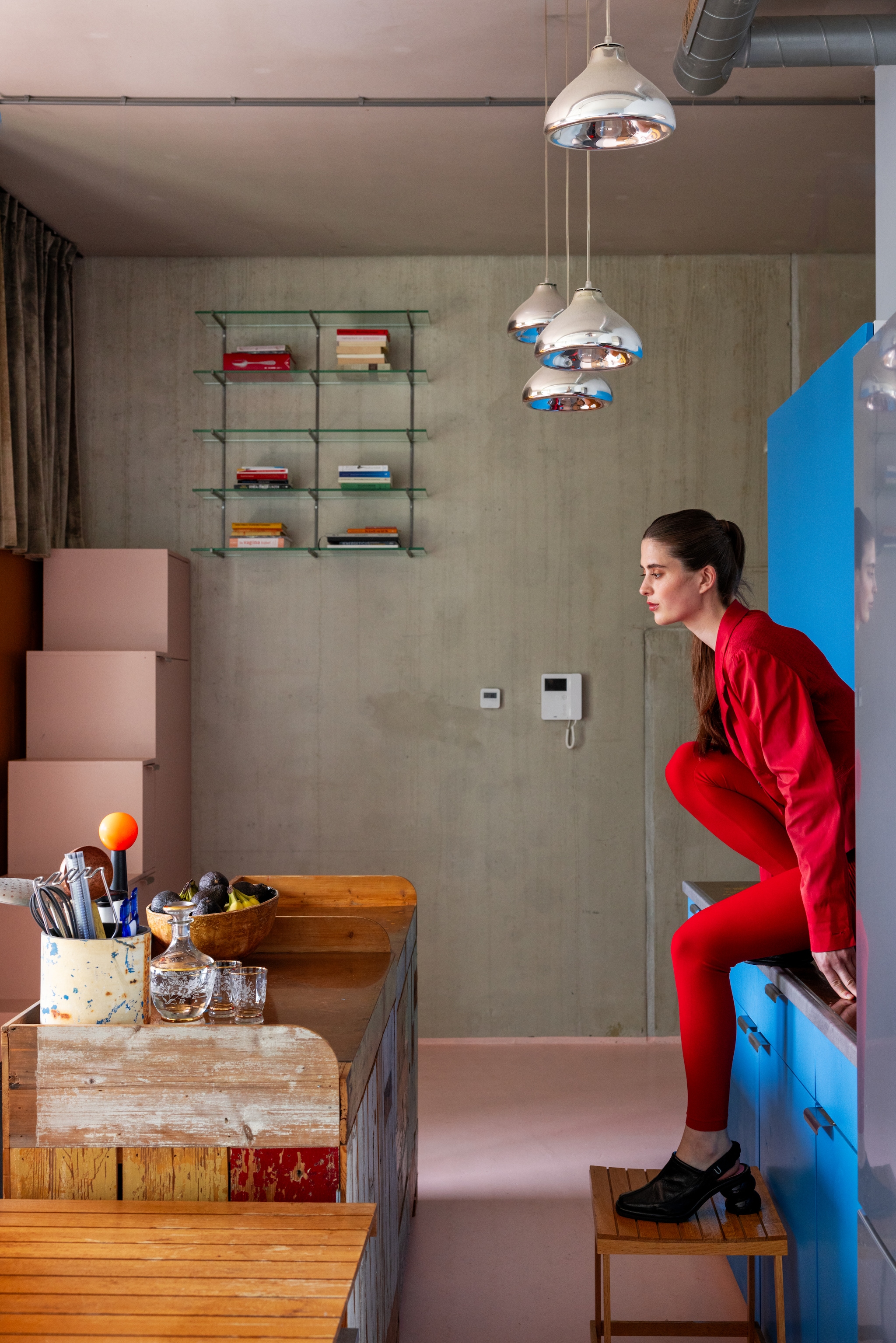 Muur van beton. Keukeneiland met koperen aanrecht en blauw gelakte kasten. Kruk Piet Hein Eek. Spatelpot zelfgemaakt van afgezaagde buis. Schaal en karaf vintage. vtwonen 10-2026 | styling Djolien De Kreij | fotografie Dana van Leeuwen