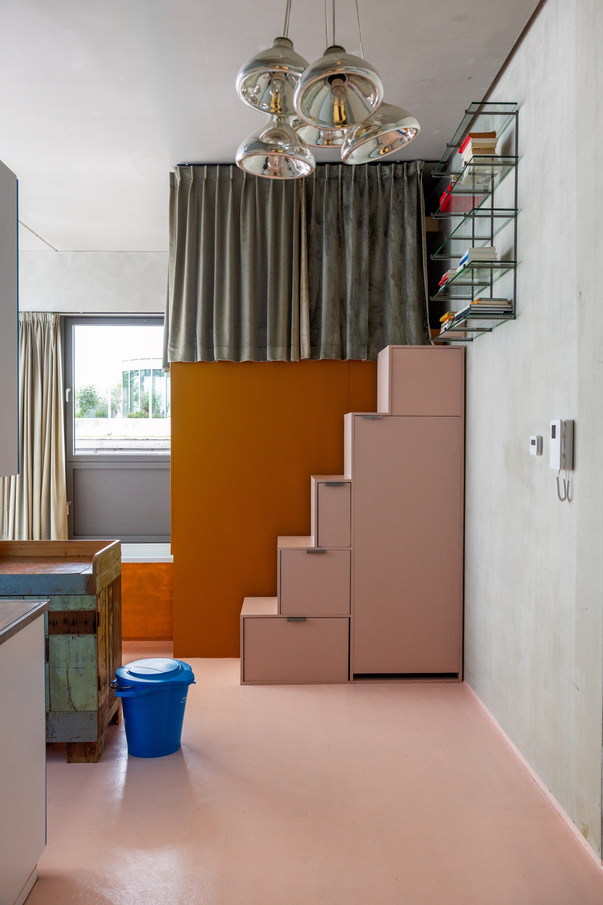 Muur van beton. Kast en gordijnen zelfgemaakt. Wandrek Piet Hein Eek. Hanglamp van oude thermoskannen. Emmer Vikan. vtwonen 10-2026 | styling Djolien De Kreij | fotografie Dana van Leeuwen