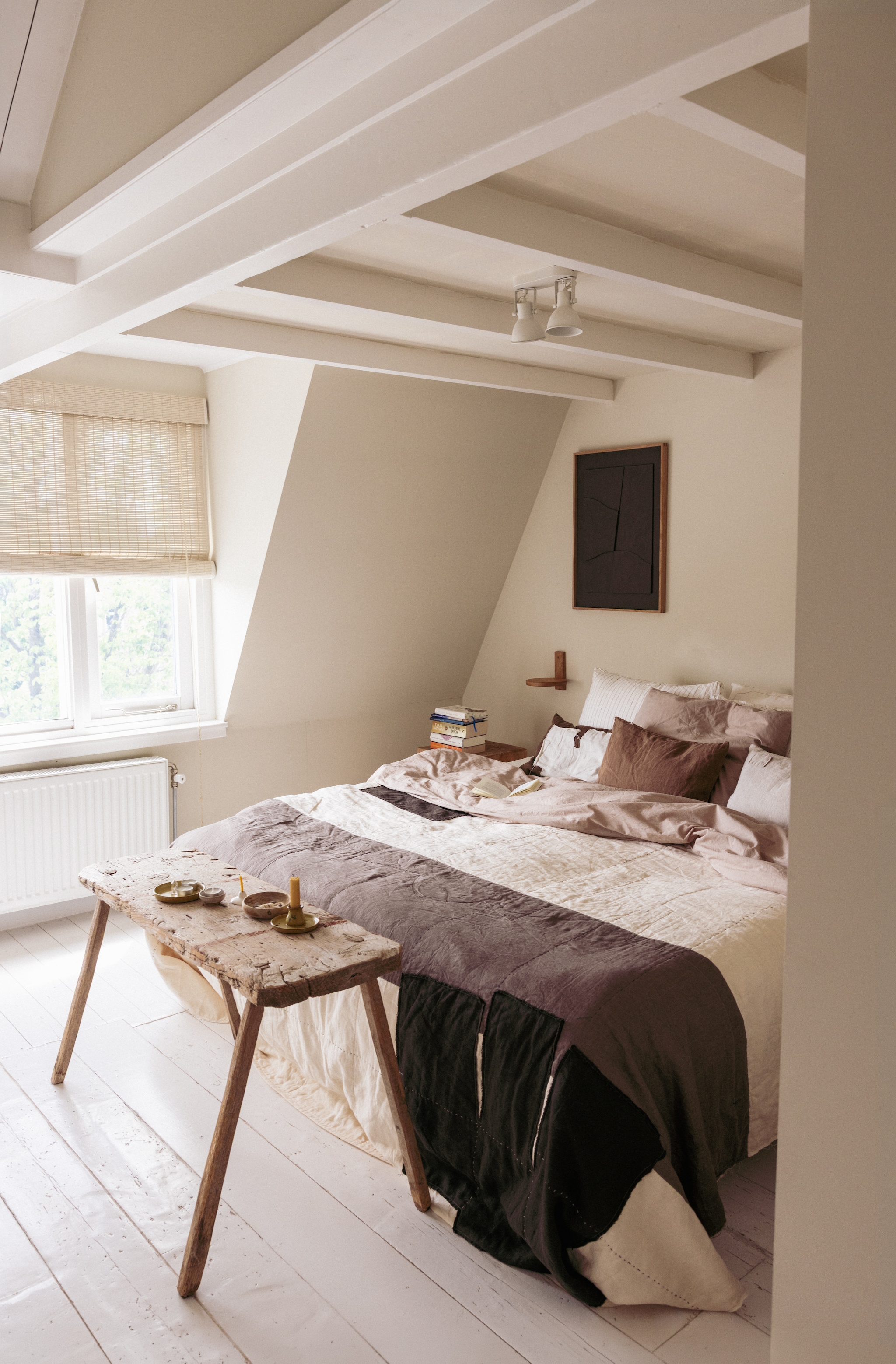 Muur kleur London Stone en vloer kleur White Tie van Farrow & Ball. Sprei XXL van Fant via Atelier Sukha. Plankje naast bed Atelier Mooijen. Kunstwerk Atelier Plateau. Beddengoed By Mölle. Rolgordijnen August Interieur. Oude bank uit Indonesië. vtwonen 10-2026 | styling Meta van Grinsven | fotografie Dana van Leeuwen