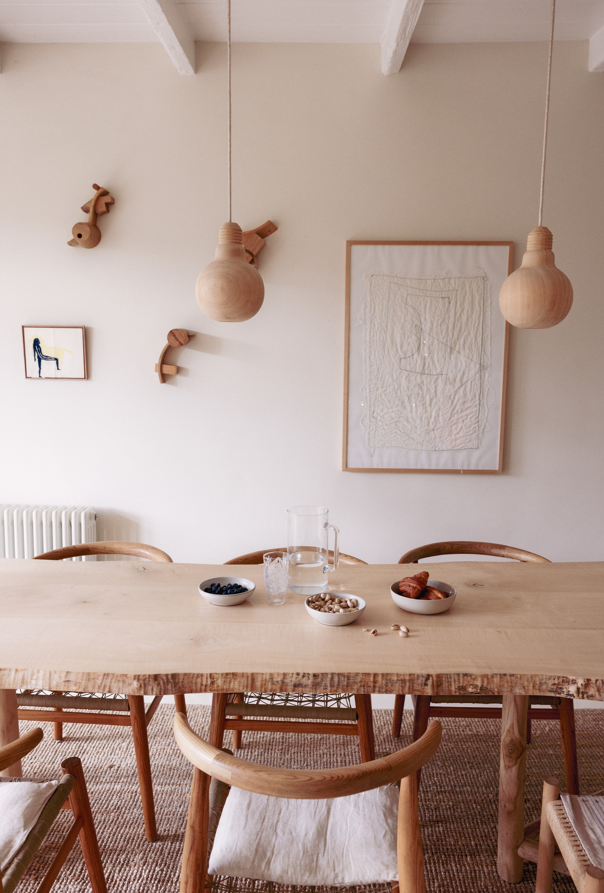 Muur kleur School House White van Farrow & Ball. Tafel gemaakt door Lumineus. Stoelen Vogel Design. Lampen From Africa With Love. Servies en kussens Atelier Sukha. Vloerkleed Ikea. Wit doek Fant. Kunstwerk paard Alexandra Duprez. Houten kunstwerken Pjotr Müller. vtwonen 10-2026 | styling Meta van Grinsven | fotografie Dana van Leeuwen