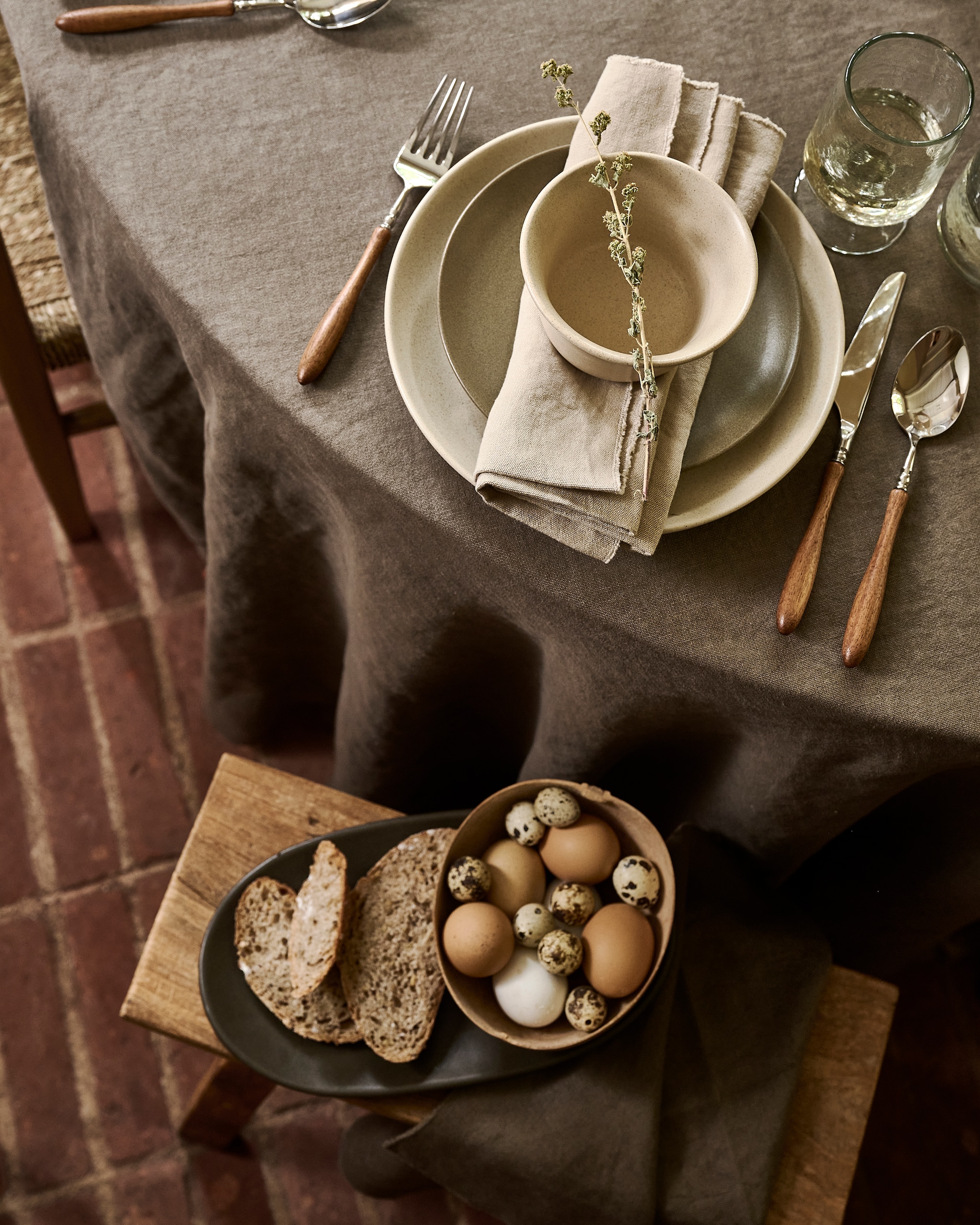 Zara Home tafelkleed, linnen € 189,-, bestek, acaciahout en metaal, set van 4 € 22,-, servetten, linnen, per stuk € 39,99 (zarahome.com). Ro Smit borden en kommen, aardewerk, beige, groen en donkergroen, per stuk vanaf € 21,51 (rosmit.nl). Urban Nature Culture wijnglazen, gerecycled glas, per stuk € 10,99 (shop.vtwonen.nl). Luksa Home Collection kruk, hout € 89,95 (luksa.furniture). vtwonen landelijk 9-2026 | Styling Danielle Verheul | Fotografie Sjoerd Eickmans