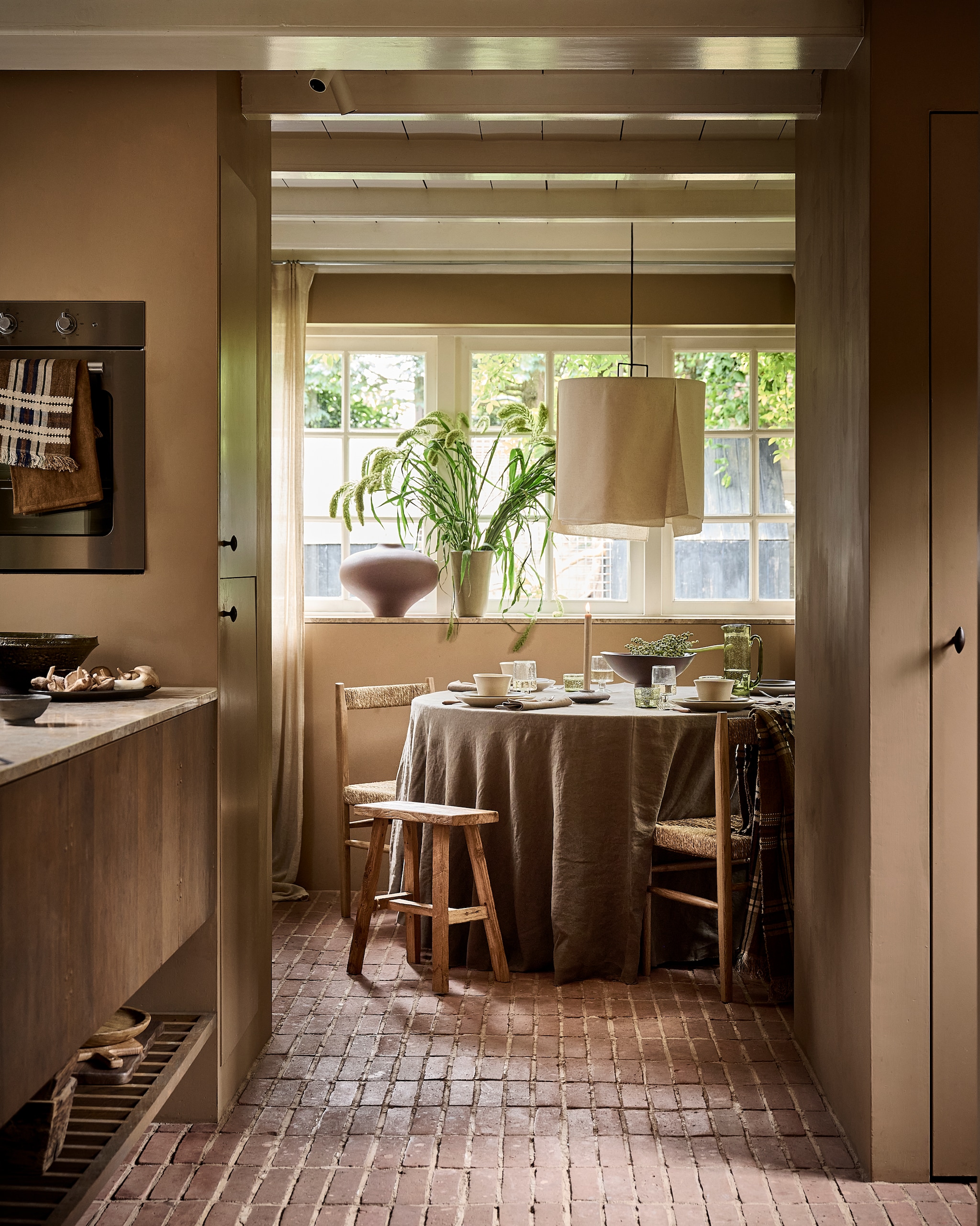 Serax hanglamp, linnen € 250,-, glazen, groen, set van 4 € 59,-, karaf, glas, groen € 59,- (serax.com). Zara Home tafelkleed, linnen € 189,-, stoelen, hout en seagrass, per stuk € 189,-, bestek, acaciahout en metaal, set van 4 € 22,99, servetten, linnen, per stuk € 39,99, kandelaar € 15,99 (zarahome.com). Ro Smit borden en kommen, aardewerk, per stuk vanaf € 21,50, vaas, aardewerk, groen € 102,50 (rosmit.nl). vtwonen schaal, aardewerk, groen € 59,99, Urban Nature Culture wijnglazen op voet, gerecycled glas, per stuk € 10,99, vaas Nomsa, keramiek, bruin € 149,99 (shop.vtwonen.nl). Libeco theedoeken, linnen, vanaf € 24,-, doek, geruit linnen € 247,- (libeco.com). Luksa Home Collection kruk, hout € 89,95, schaaltje, keramiek, grijs € 7,50, bakken, verweerd hout, per stuk € 34,95 (luksa.furniture). Overig privébezit. styling Danielle Verheul | fotografie Sjoerd Eickmans