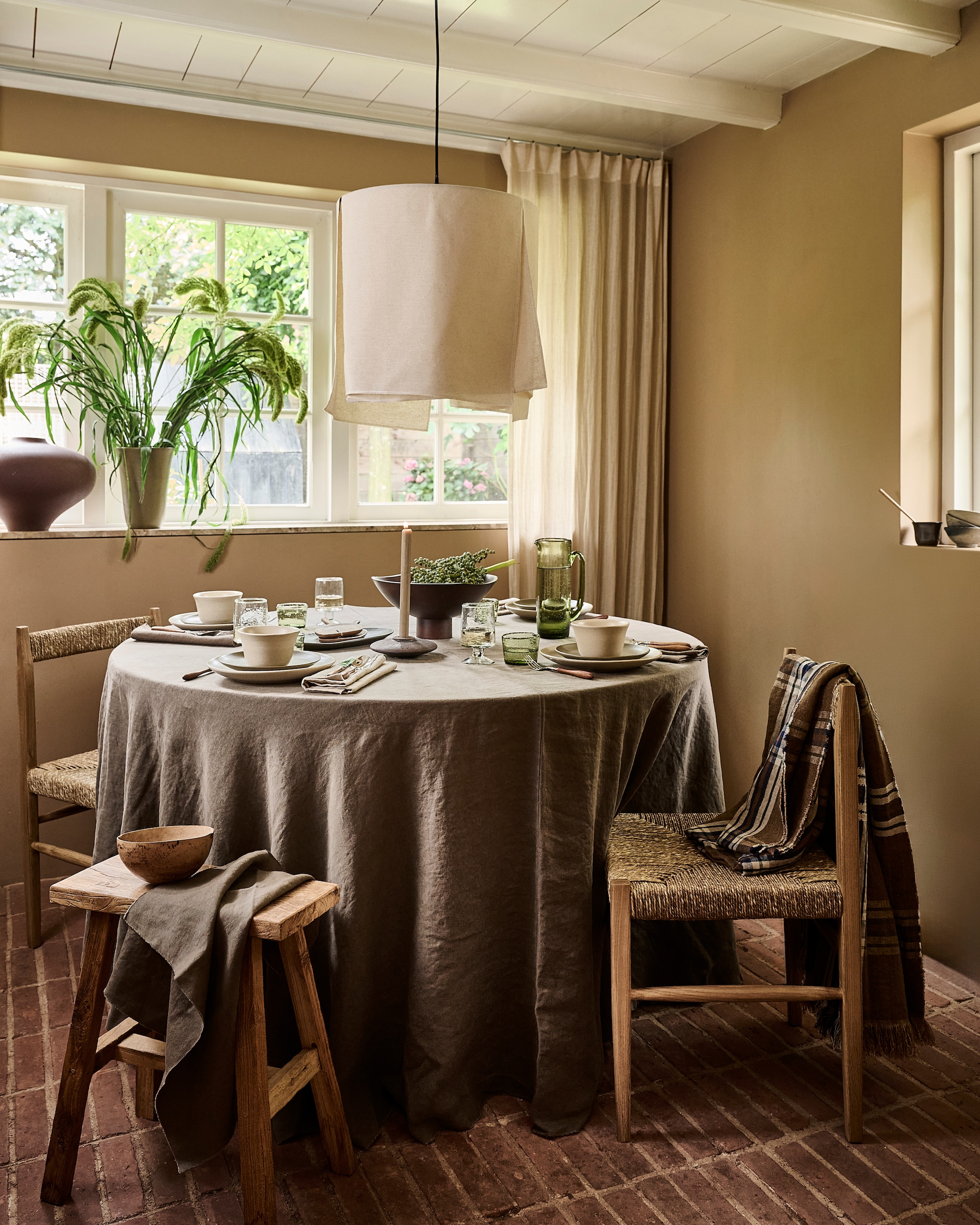Zara Home tafelkleed, linnen € 189,-, servetten, linnen, per stuk € 39,99, bestek, acaciahout en metaal, set van 4 € 22,99, kandelaar € 15,99, eetkamerstoel, hout en seagrass € 189,- (zarahome.com). Ro Smit borden en kommen, aardewerk, per stuk vanaf € 21,50 (rosmit.nl). Serax glazen, groen, set van 4 € 59,-, karaf, glas, groen € 59,- (serax.com). Urban Nature Culture wijnglazen, gerecycled glas € 10,99, schaal Orion op voet, aardewerk € 149,99 (shop.vtwonen.nl). Libeco tafelkleed, linnen, geruit € 247,- (libeco.com). Luksa Home Collection kruk, hout € 89,95 (luksa.furniture). vtwonen landelijk 9-2026 | Styling Danielle Verheul | Fotografie Sjoerd Eickmans