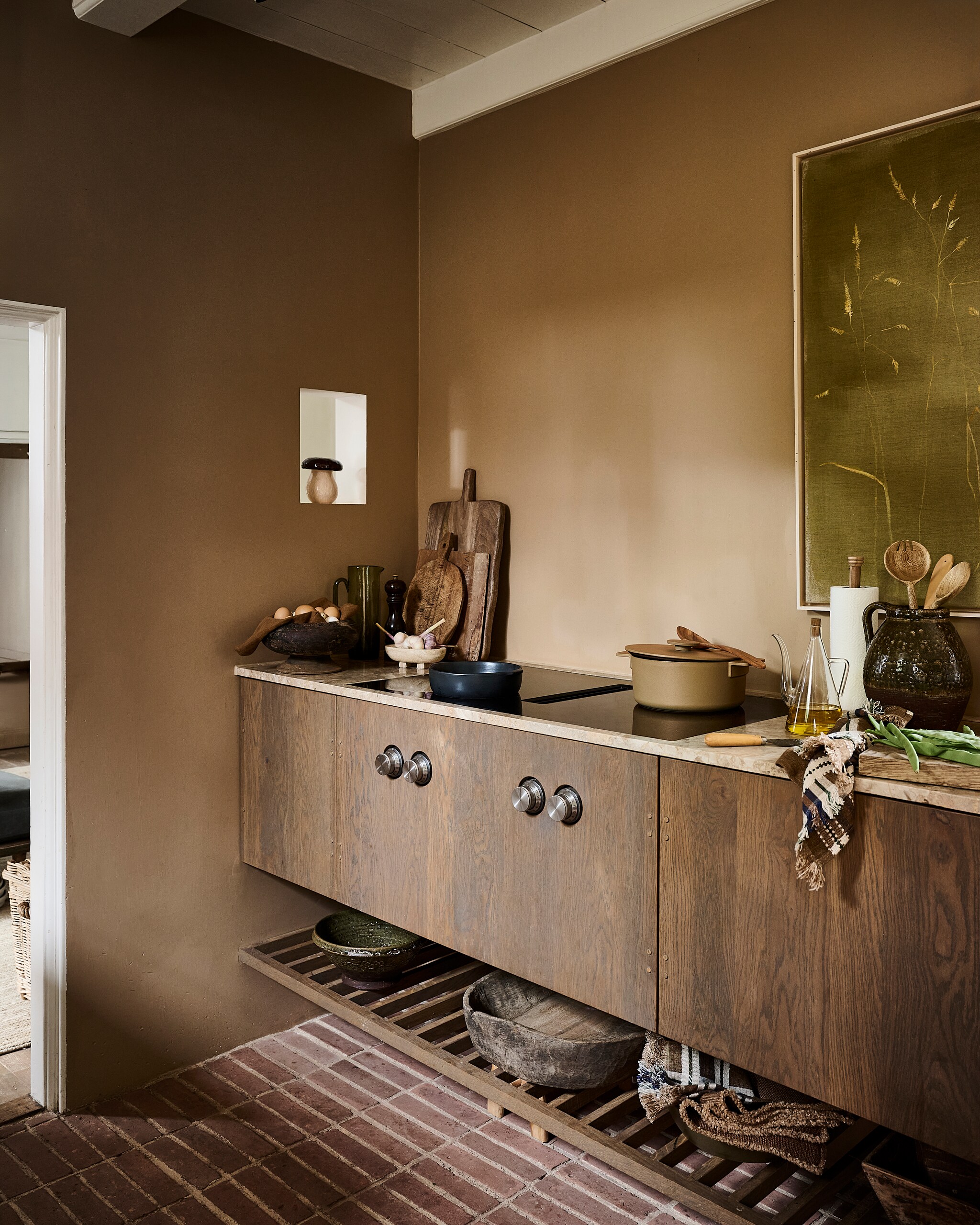 Arket opberger paddenstoel, keramiek € 39,99 (arket.com). Luksa Home Collection schaal op voet, hout € 79,95, schaal, hout € 79,95 (luksa.furniture). Serax karaf, glas, groen € 59,-, ovenschaal, zwart € 35,-, pan, gietijzer, groen € 225,- (serax.com). Studio Bazar pepermolen, hout € 49,95, pollepels, walnoothout, vanaf € 4,95 (studiobazar.com). Pand40 schaaltje op pootjes, steen € 25,76 (pand-40.nl). Zara Home plank, hout € 29,99, keukenrolhouder, hout € 15,99, olijfoliefles € 17,99 (zarahome.com). vtwonen collectie pot, keramiek, groenbruin € 89,95, schaal, keramiek, groen € 59,95 (shop.vtwonen.nl). Libeco theedoek, linnen, geruit € 45,-, placemat, linnen, bruin € 42,- (libeco.com). Schilderij Grassen op mosgroen € 1100,- (maartjevandennoort.nl). Overig privébezit. vtwonen landelijk 9-2026 | styling Danielle Verheul | fotografie Sjoerd Eickmans