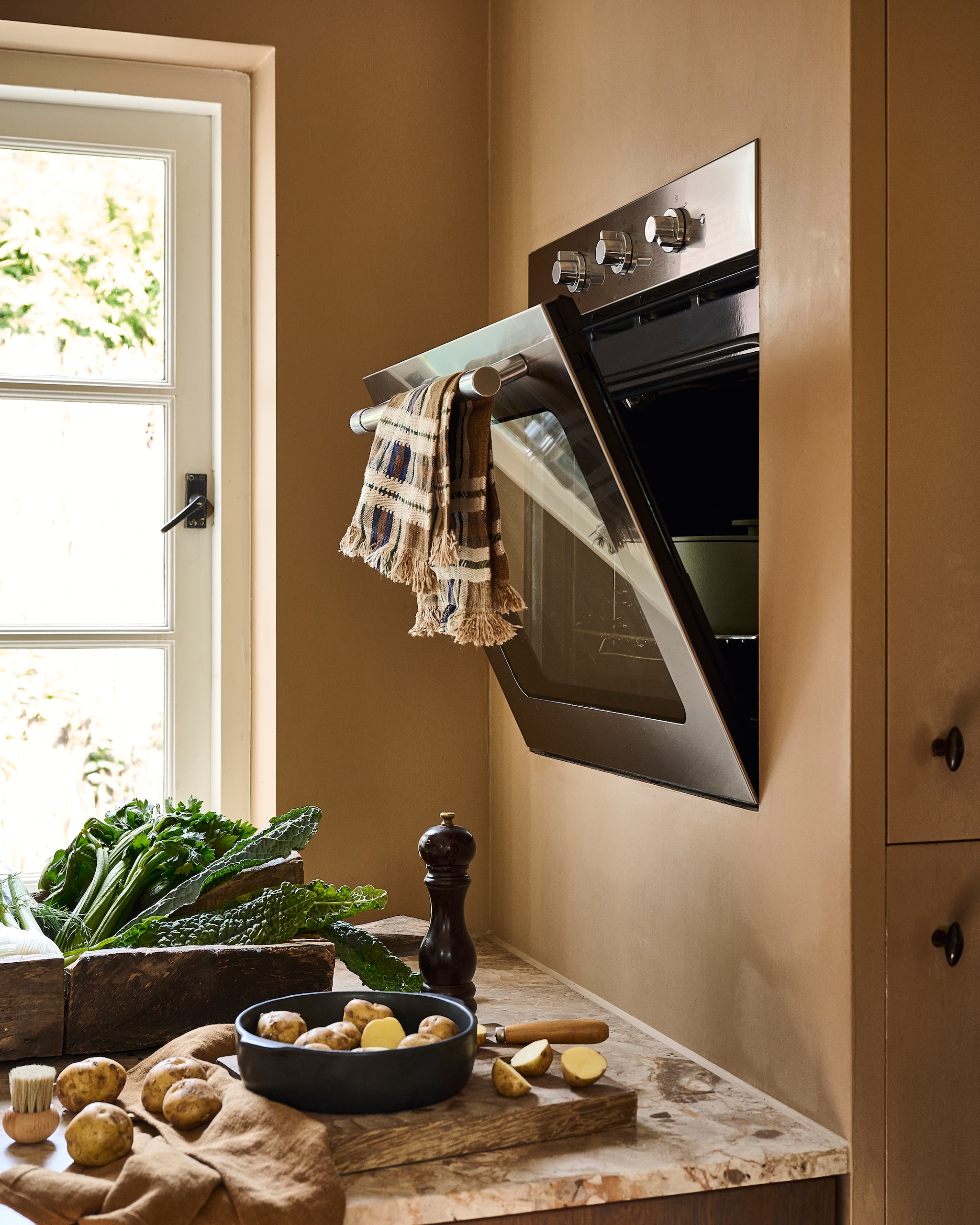 Ikea oven (ikea.com). Luksa Home Collection bak, verweerd hout € 179,- (luksa.furniture). Serax ovenschaal, zwart € 35,- (serax.com). Studio Bazar borstel, hout € 6,25, pepermolen, hout € 49,95 (studiobazar.com). Libeco keukendoek, linnen, geruit € 45,-, theedoek, linnen, bruin € 35,- (libeco.com).  Overig privébezit. vtwonen landelijk 9-2026 | styling Danielle Verheul | fotografie Sjoerd Eickmans