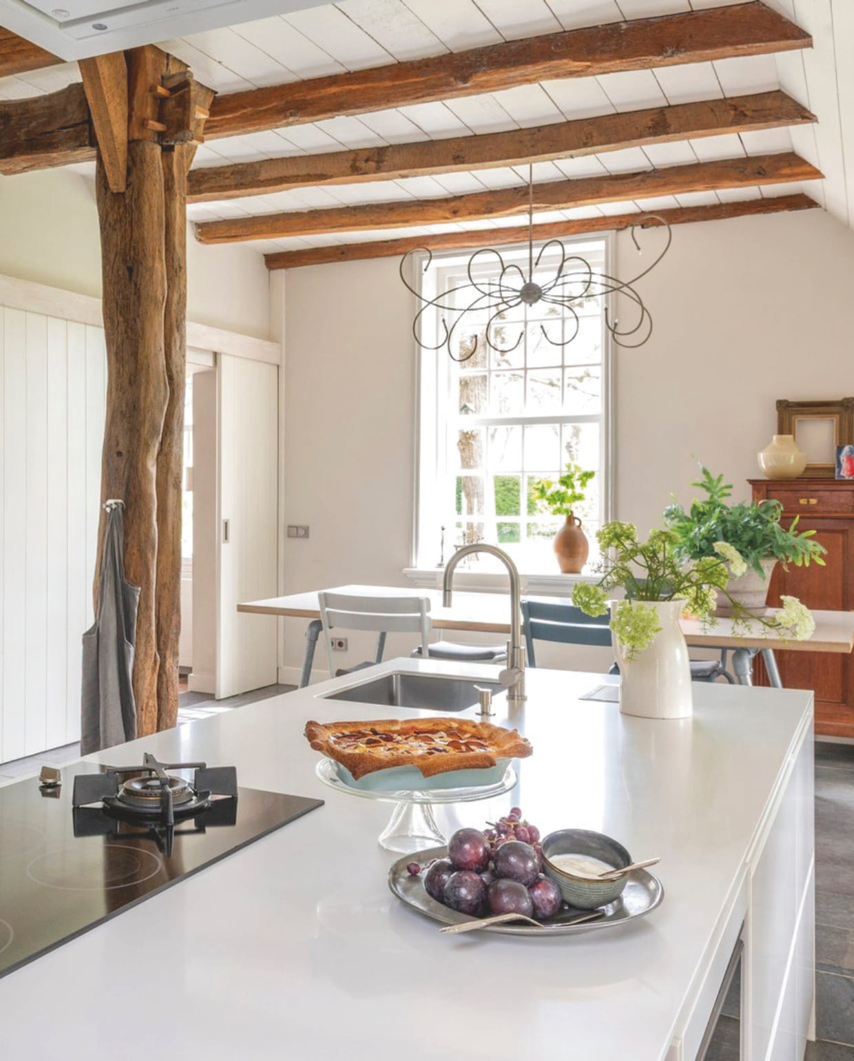 Keuken Tulp. Eettafel gemaakt door Roel Westerman. Eettafelstoelen Fermob. Witte kan brocante. Tinnen dienblad brocante. vtwonen Landelijk 7-2026 | fotografie Suzanne Paap