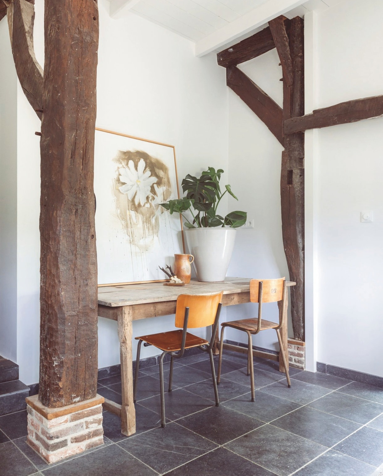 Schilderij Gea Slotman. Houten bank maatwerk Roel Westerman. Rotan poefs Anne-Marie Wonen. Leren stoel vintage. Schapenvacht Studio Hebbe!. vtwonen Landelijk 7-2026 | fotografie Suzanne Paap