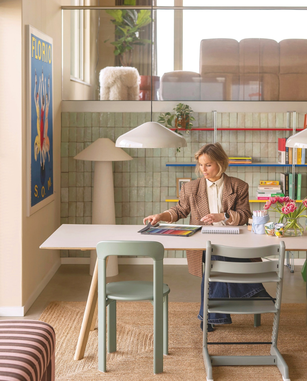 Tafel, stoelen en hanglampen Hay. Kinderstoelen Tripp Trapp van Stokke. Vloerkleed Zara Home. Kunstwerk Florio van Leonetto Cappiello via Werk aan de Muur. Staande lamp Kwantum. Tegels Platta Vert Clair via Designtegels. Eetkamerbank Lobby van HKliving. Boekenkast Ikea. Muurkleur Joa’s White van Farrow & Ball. Vloer Stanmore dryback beige van Floorlife.