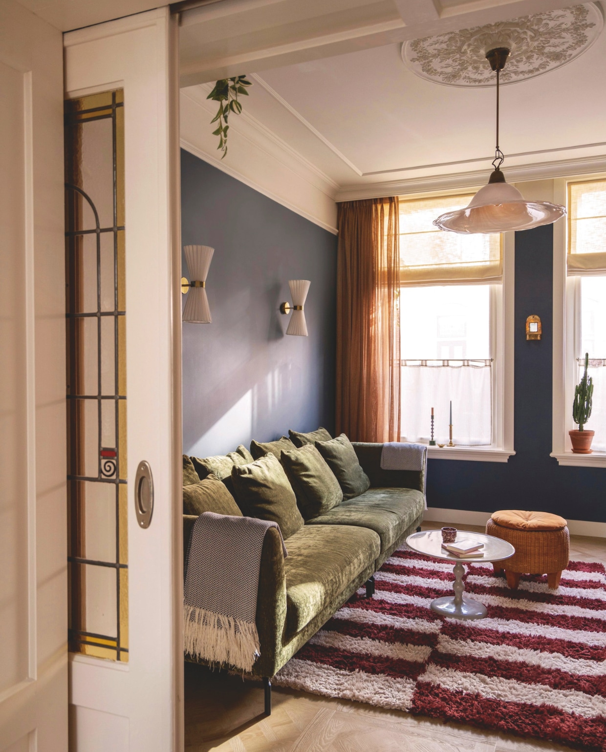Vloerkleed Block van Loods 5. Wandlampen Telang van Beliani. Bank Homestock. Salontafel Table basse ronde Leen Bakker. Hanglamp en poef kringloopwinkel. Verfkleur Stiffkey Blue van Farrow & Ball. Rozet en sierlijsten Het Schippertje. vtwonen 09-2026 | fotografie Lotte van Uittert