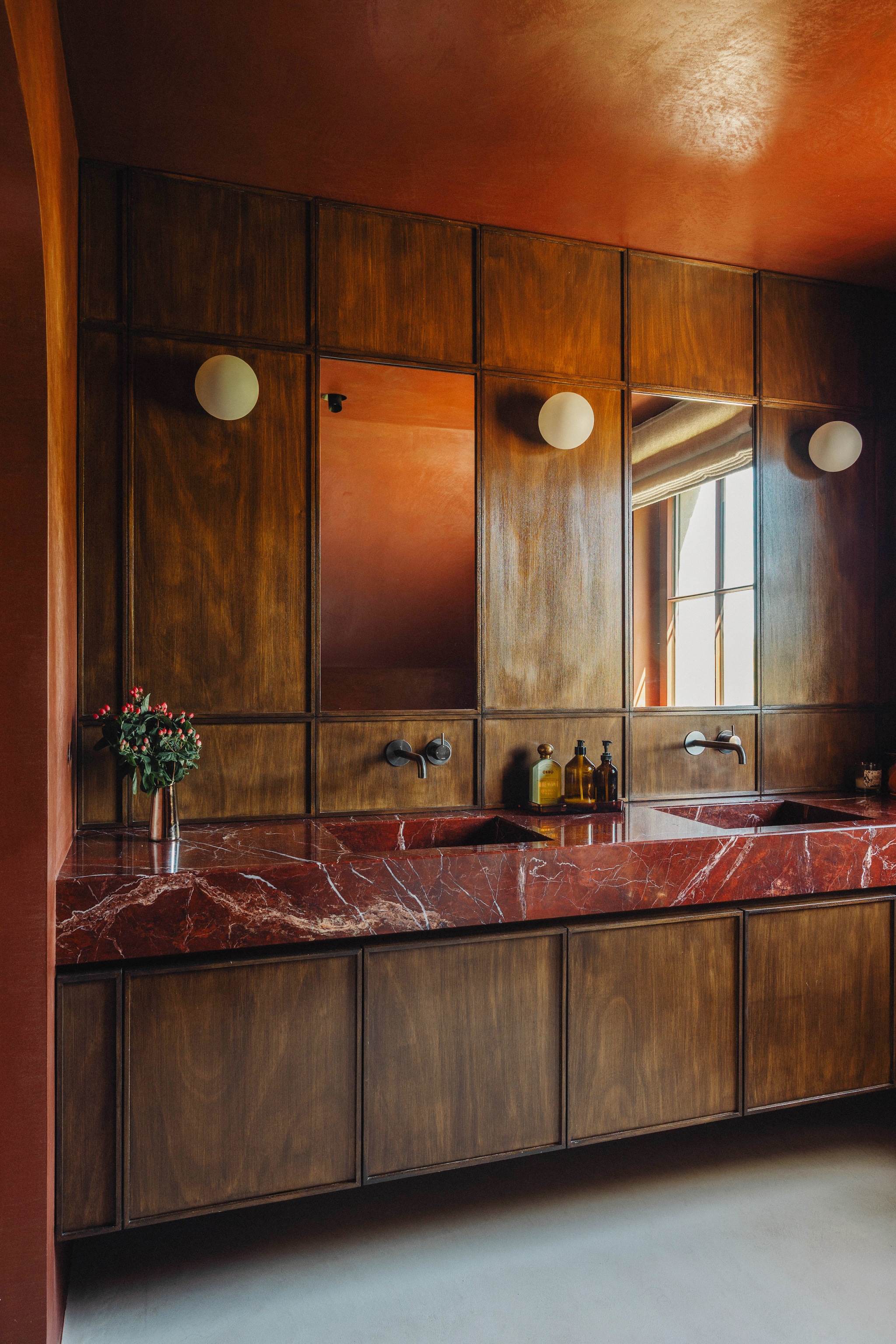 De badkamer is een ontwerp van Julie. Wastafel van gepolijste rode jaspis via Bmb Natuursteen, gemaakt door Artimar. Houtfineer Bosq. Kranen Hotbath. Wandlampen Dioscuri van Artemide en Invisible Wall Light van Prado. Lichaamsolie Kiso Yuzu van Officine Universelle Buly en geurkaars Candle N°1 van Gachon Pothier. vtwonen Design 9-2026 | fotografie Stie De Neve