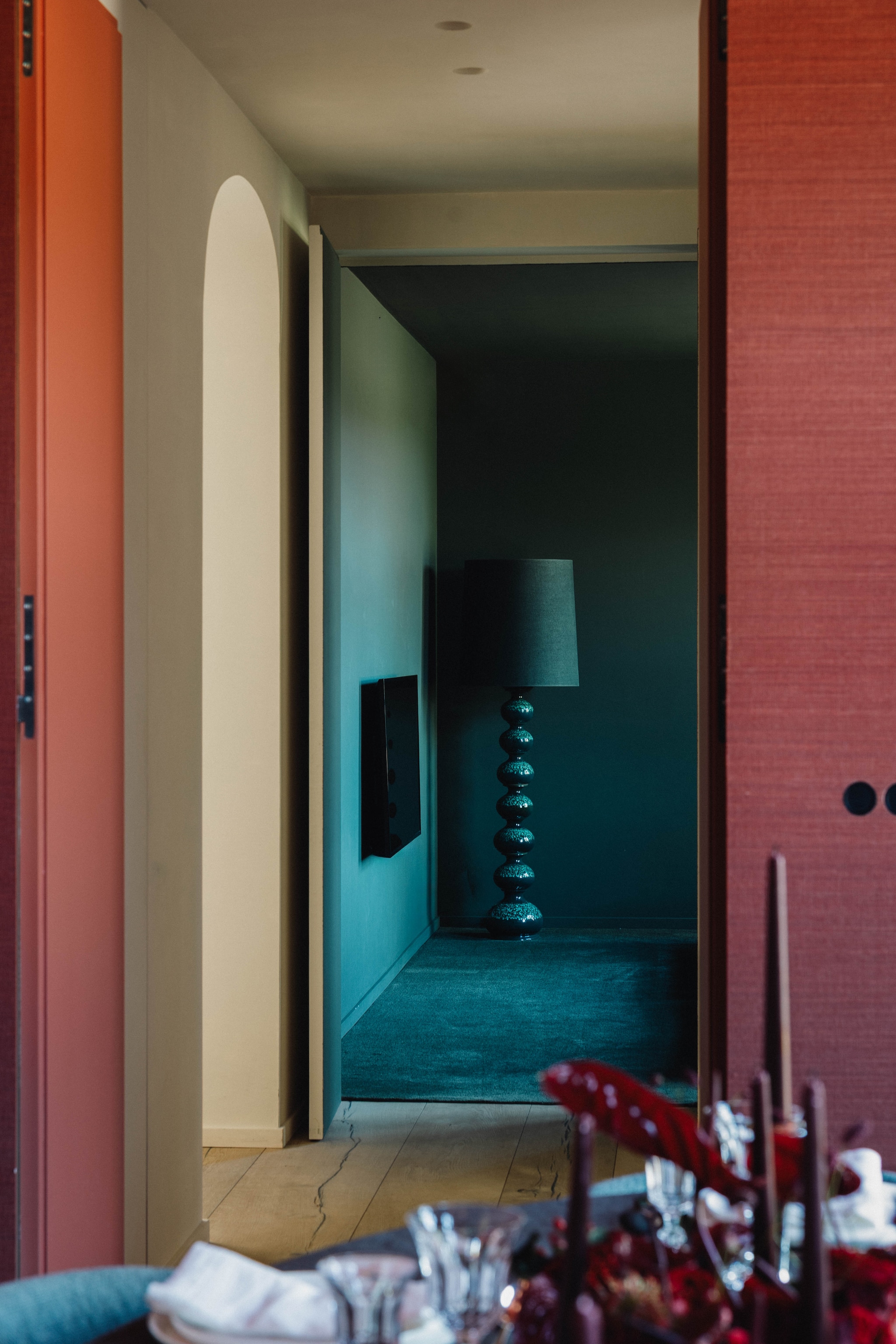 Vanuit de rode kamer een blik op de groene tv-kamer. Vintage lamp Kaiser Leuchten, kap van René Houben. Houten plankenvloer Nobel Flooring. vtwonen Design 9-2026 | fotografie Stie De Neve