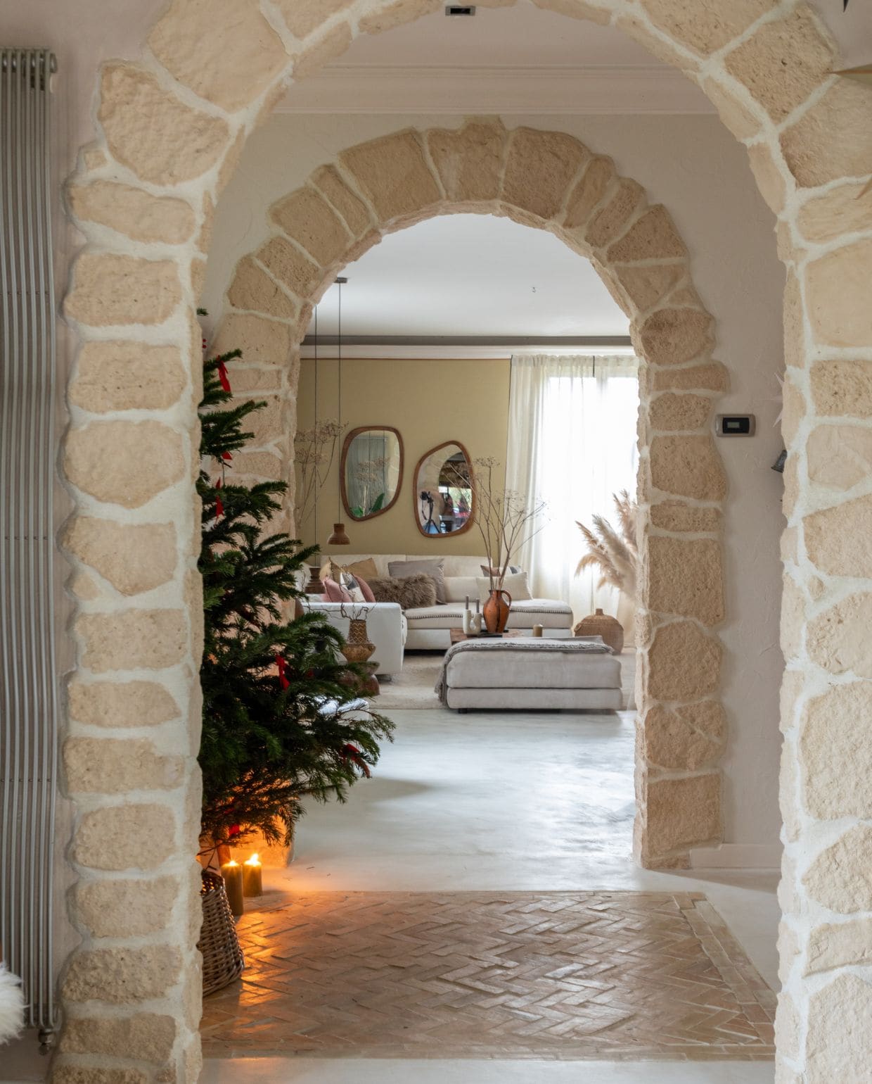 Gepolijste betonnen vloer in Isatis van Maison Étanche. Terracotta vloer Maison Zellige. Bank en hocker Poltronesofà. Vloerkleed Decoweb. Spiegels Made in Meubles. vtwonen Kerstspecial 2025 | styling Marie-Maud Levron | fotografie Cecile Perrinet Lhermitte