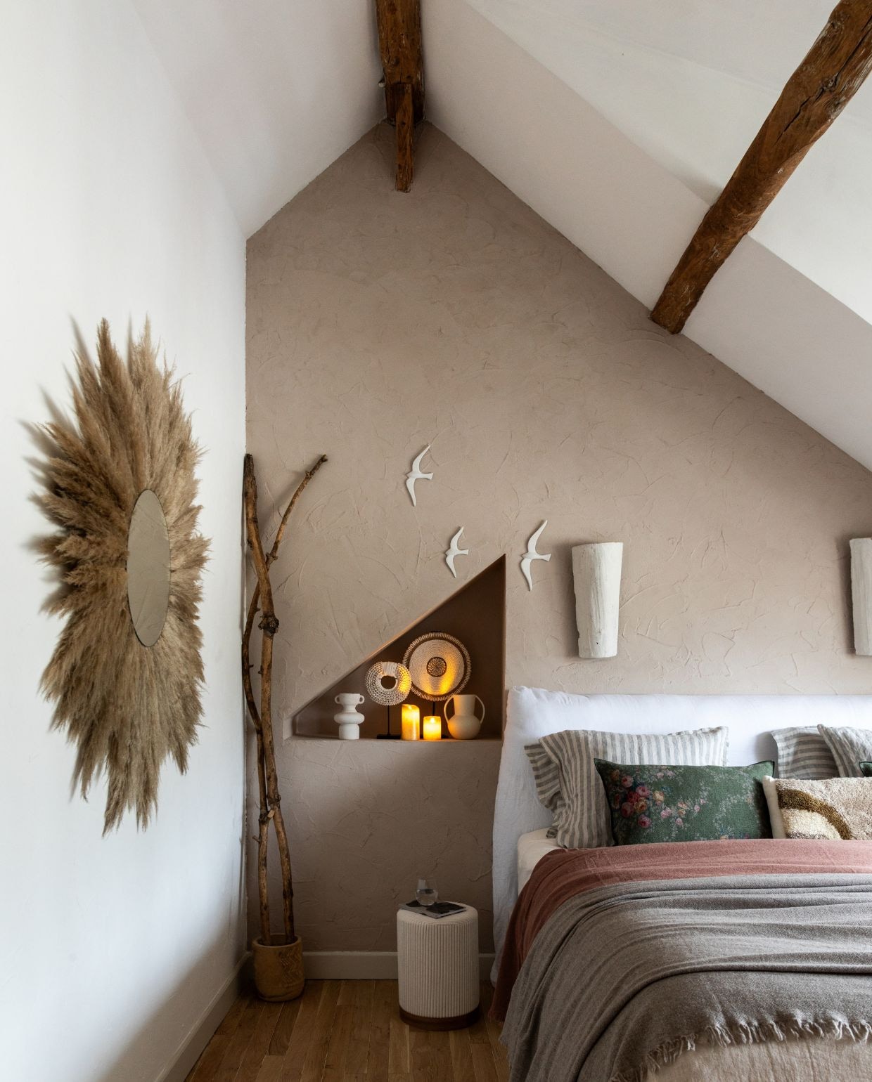 Kalkverf achter het bed Noce van Kalklitir. Muurverf andere muren White Velvet van V33. Wandlampen van oude dakpannen, gemaakt door Eve. Spiegel met gevonden pluimen, gemaakt door Eve. Poef en vazen L’Incroyable. Keramieken zwaluwen Leboncoin. Beddengoed Maison de Vacances. Kussenhoezen Le Monde Sauvage. vtwonen Kerstspecial 2025 | styling Marie-Maud Levron | fotografie Cecile Perrinet Lhermitte