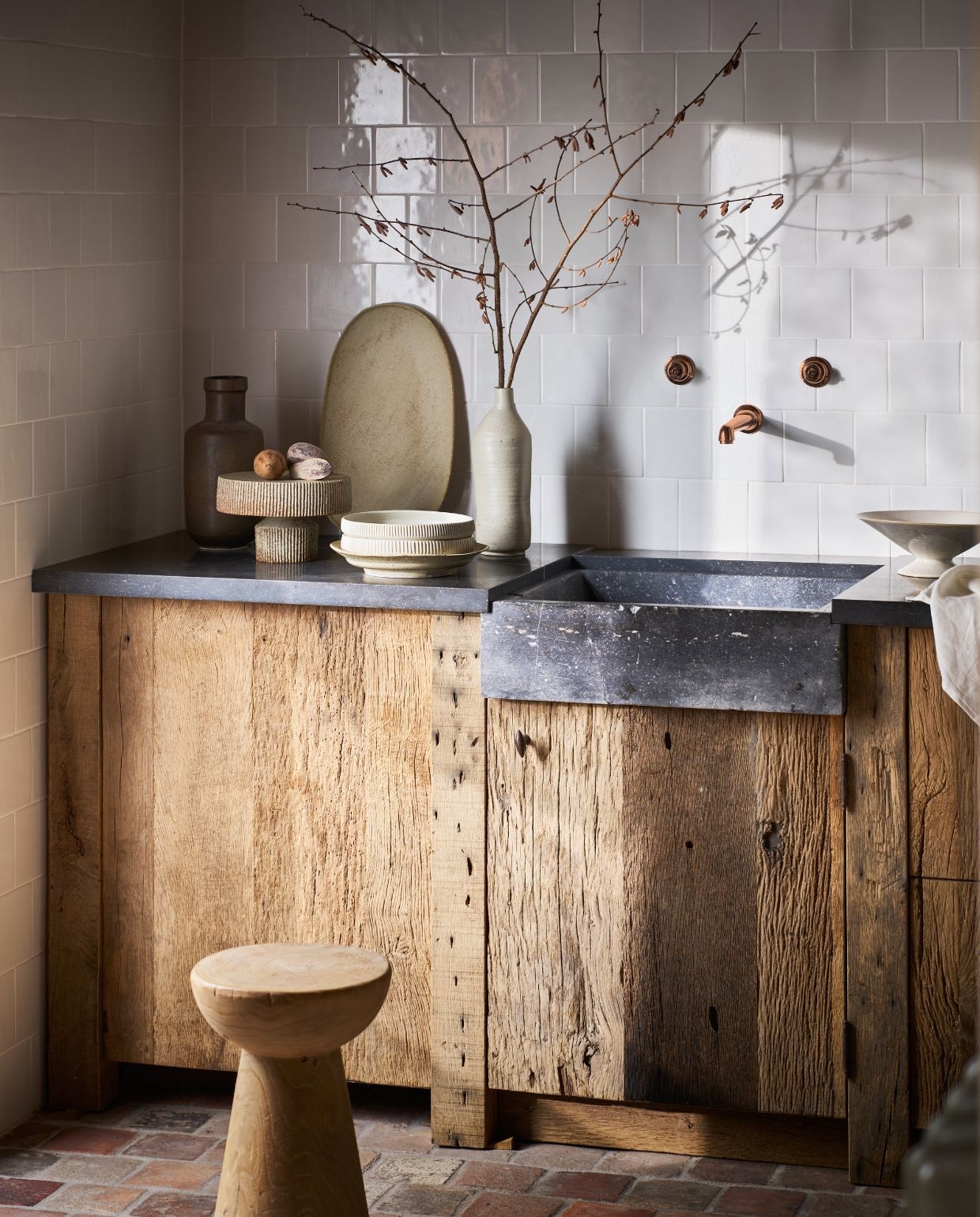Marjoke de Heer schalen, keramiek, flessen, prijs op aanvraag (marjokedeheer.com). Zara Home schaal, op voet € 39,99 (zarahome.nl). ’t Achterhuis kruk, hout € 217,80, keukenunit, oud hout en natuurstenen bak en blad, 220x65x93 cm (bxdxh) € 10.103,50, plavuizen, antiek, zalm genuanceerd, per m² € 119,79, wandtegels Hollandse witjes, 13x13 cm (bxh), per m² € 163,35 (achterhuis.nl). vtwonen Landelijk 10-2026 | styling Cleo Scheulderman | fotografie Jeroen van der Spek